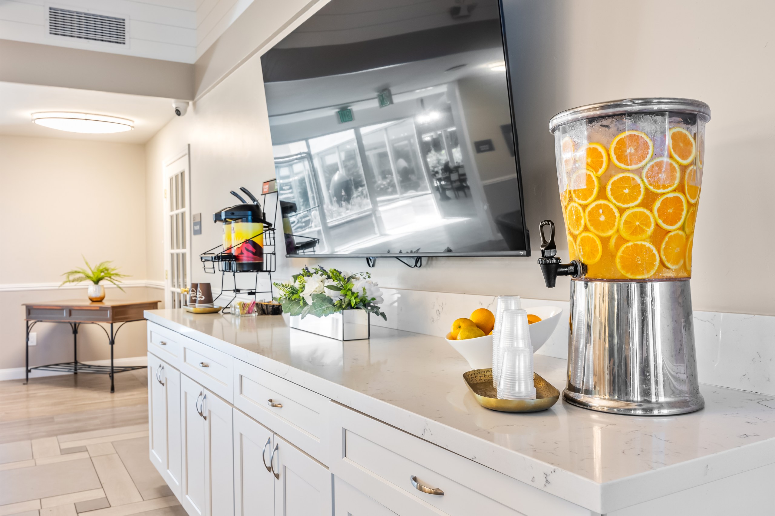 A kitchen with a white countertop and a silver container with orange slices on it.