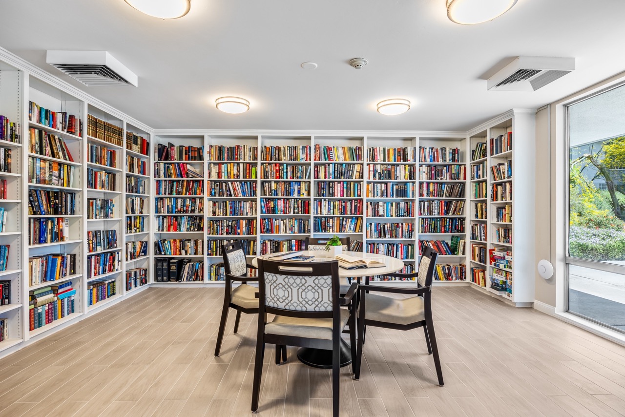 Library lined with bookshelves with a table and chairs in the center.