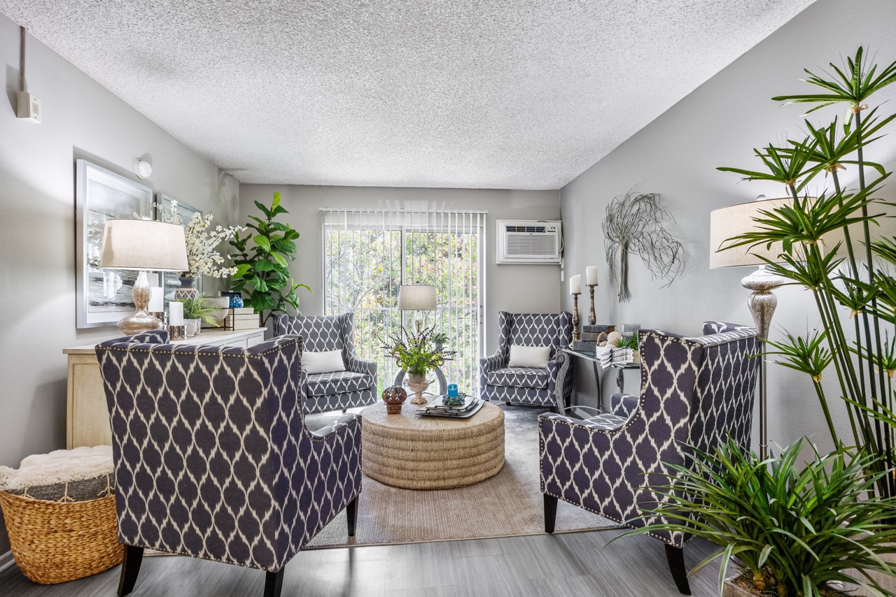 A living room with a grey patterned chair and a round wicker table.