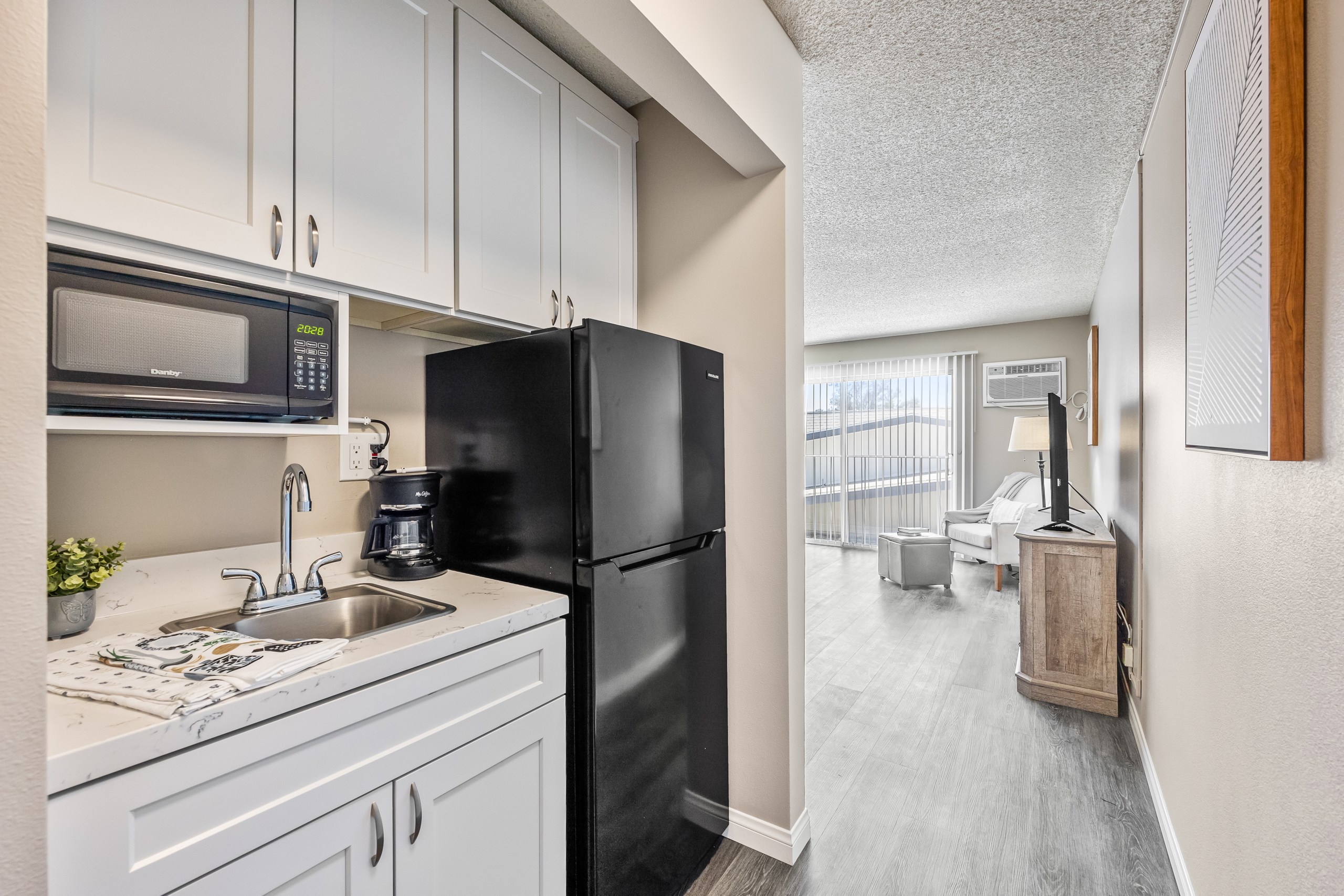 A black refrigerator in a kitchen with white cabinets.