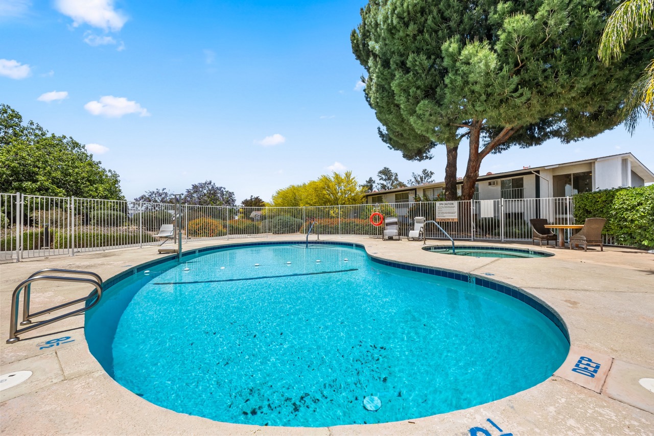 A large blue swimming pool surrounded by a fence and trees.